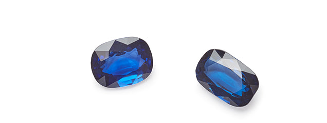 An image of 2 cushion shaped blue sapphire stones on a flat surface
