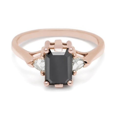 A three stone engagement ring with an emerald cut and emerald shape 7x5mm black diamond center stone with two white diamond trillion side stones set in rose gold., Rose Gold 3