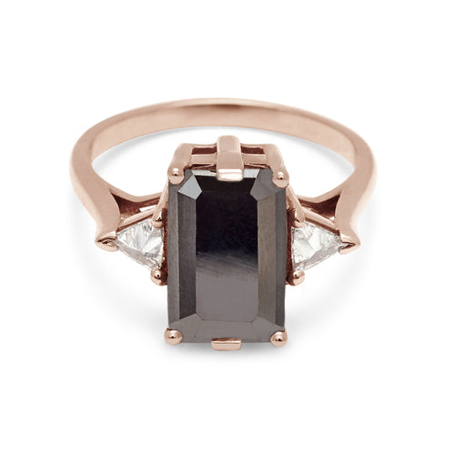 A three stone engagement ring with an emerald shape black diamond center stone with two white diamond trillion side stones set in rose gold., Rose Gold
