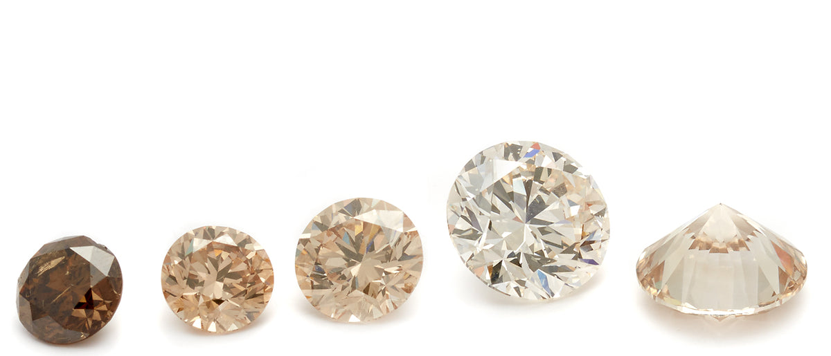 5 round cut diamonds sit horizontally across the image, graduating in color from dark cognac diamond to light champagne diamond