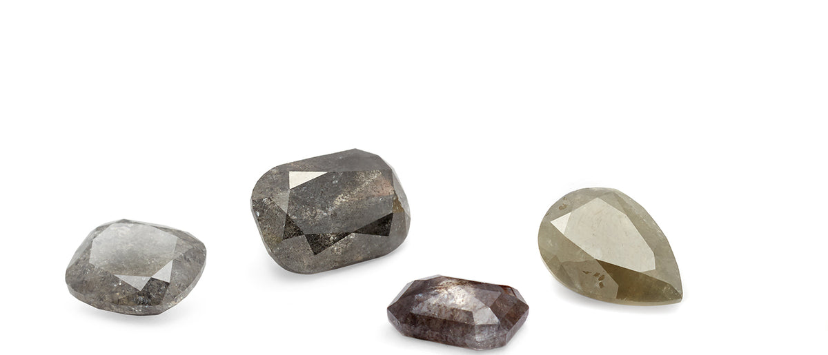 4 grey diamonds sit on a flat surface with varying colors, shapes, and sizes.