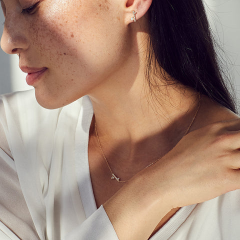 A medium-complexion model wears a diamond dusted meridian necklace with white diamonds and one stud on her ear with an opal accent stone. 3