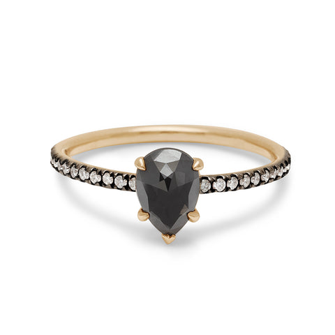 A solitaire pear shaped black diamond ring with claw prongs with white diamond pave on the band set in black rhodium and yellow gold.