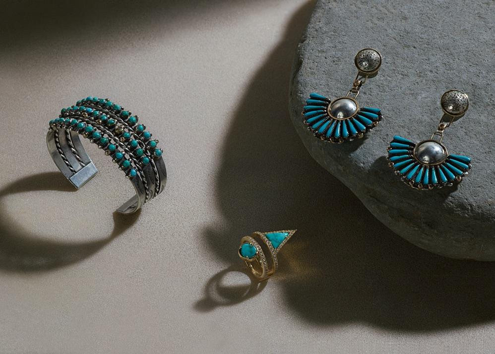 An image of a turquoise bracelet, turquoise ring, and turquoise earrings propped on top of natural stones with moody shadow lighting.
