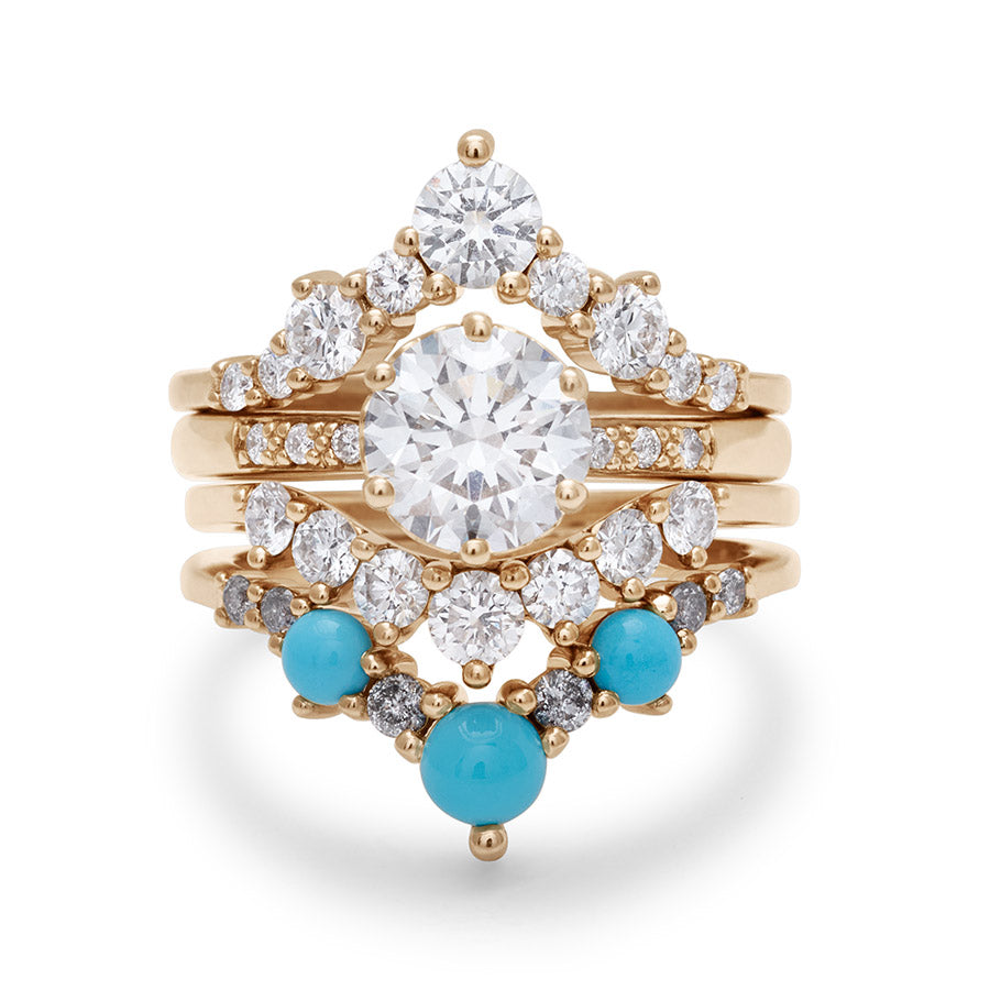 A solitaire round white diamond engagement ring stacked between two chevron bands and a curve band with white diamonds and turquoise stones.