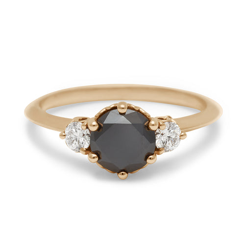 A three stone engagement ring with a round shape black diamond center stone with two white diamond round side stones set in yellow gold., Yellow Gold