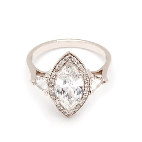 A three stone engagement ring with a marquise shape 1.50ct white diamond center stone surrounded by a white diamond pave halo with two white diamond trillion side stones set in platinum. 5