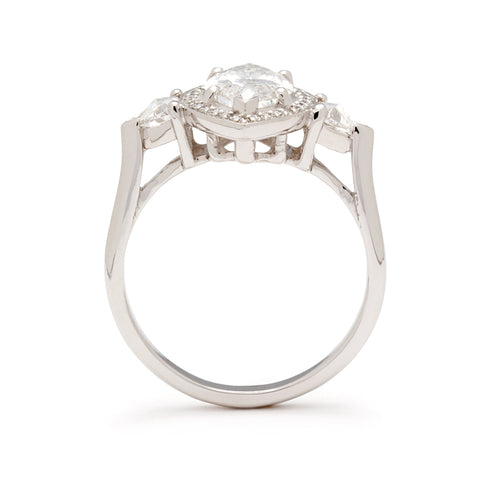 Side view of a three stone engagement ring with a marquise shape 1.50ct white diamond center stone surrounded by a white diamond pave halo with two white diamond trillion side stones set in platinum. 7