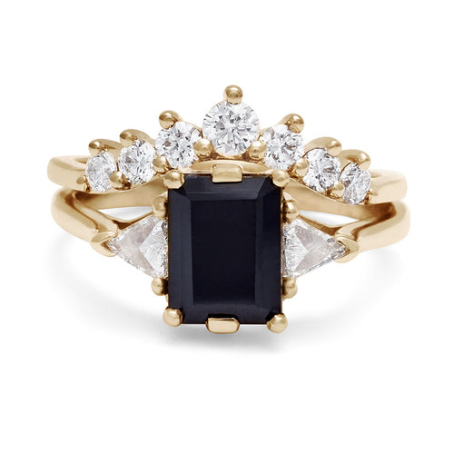 A three stone engagement ring with an emerald cut and emerald shape 8x6mm black diamond center stone with two white diamond trillion side stones set in yellow gold above a 7 white diamond curve band., White Gold, Rose Gold, Yellow Gold