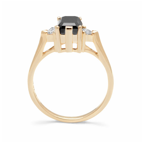 Side view of a three stone engagement ring with an emerald cut and emerald shape 7x5mm black diamond center stone with two white diamond trillion side stones set in yellow gold., Yellow Gold