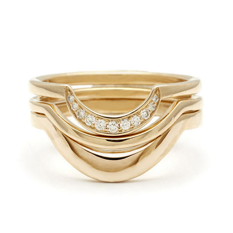 Two solid yellow gold curve bands stacked beneath a crescent shaped white diamond band in yellow gold.