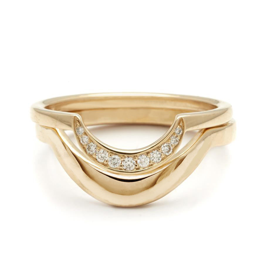 A solid yellow gold curve band stacked beneath a crescent shaped white diamond band in yellow gold.