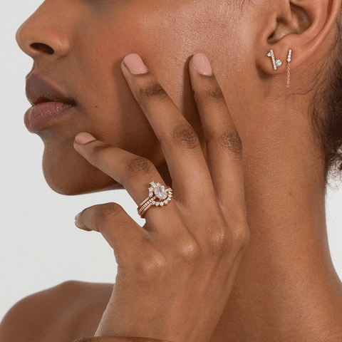 A single earring with a straight line of white diamond pave with white diamond accent stones on either side set in a yellow gold on a darker-complextion model's ear with a stack of three rings on her ring finger., White Gold, Rose Gold, Yellow Gold 6