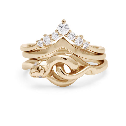 A serpent band with white diamond eyes set in yellow gold stacked below a solid gold nesting band and a white diamond nesting band.