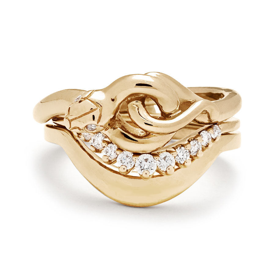 A serpent band with two white diamonds for eyes stacked above an 11 white diamond curve band and a tapered solid gold band in yellow gold.