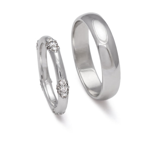 A five cluster white diamond band in white gold next to a 5mm classic round band set in white gold.