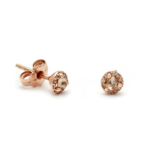 A pair of tiny champagne diamond center stone earrings with a halo of champagne diamond set in rose gold one earring angled. 2