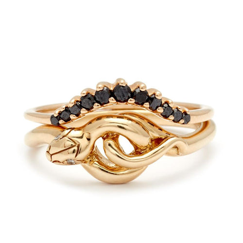 A serpent band with white diamonds for eyes set in yellow gold with a black diamond curve band stacked above.