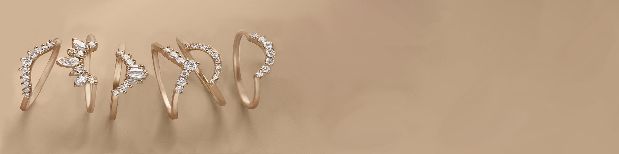 Cascading array of white diamond bands set in yellow gold on a peach colored background.