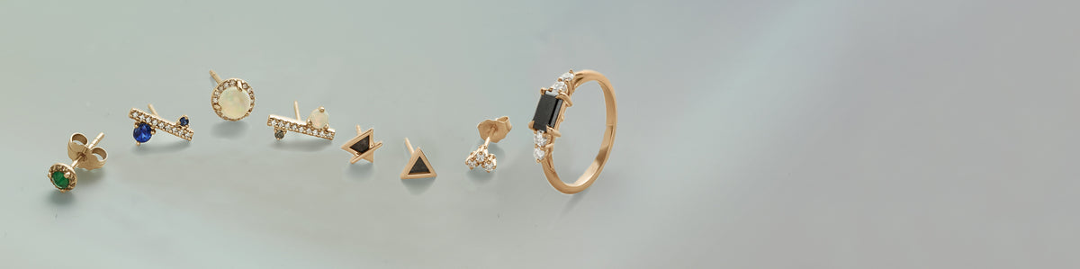 A line of 7 different silhouettes of earring with different gemstones with a five stone engagement ring at the end on a colorful background.
