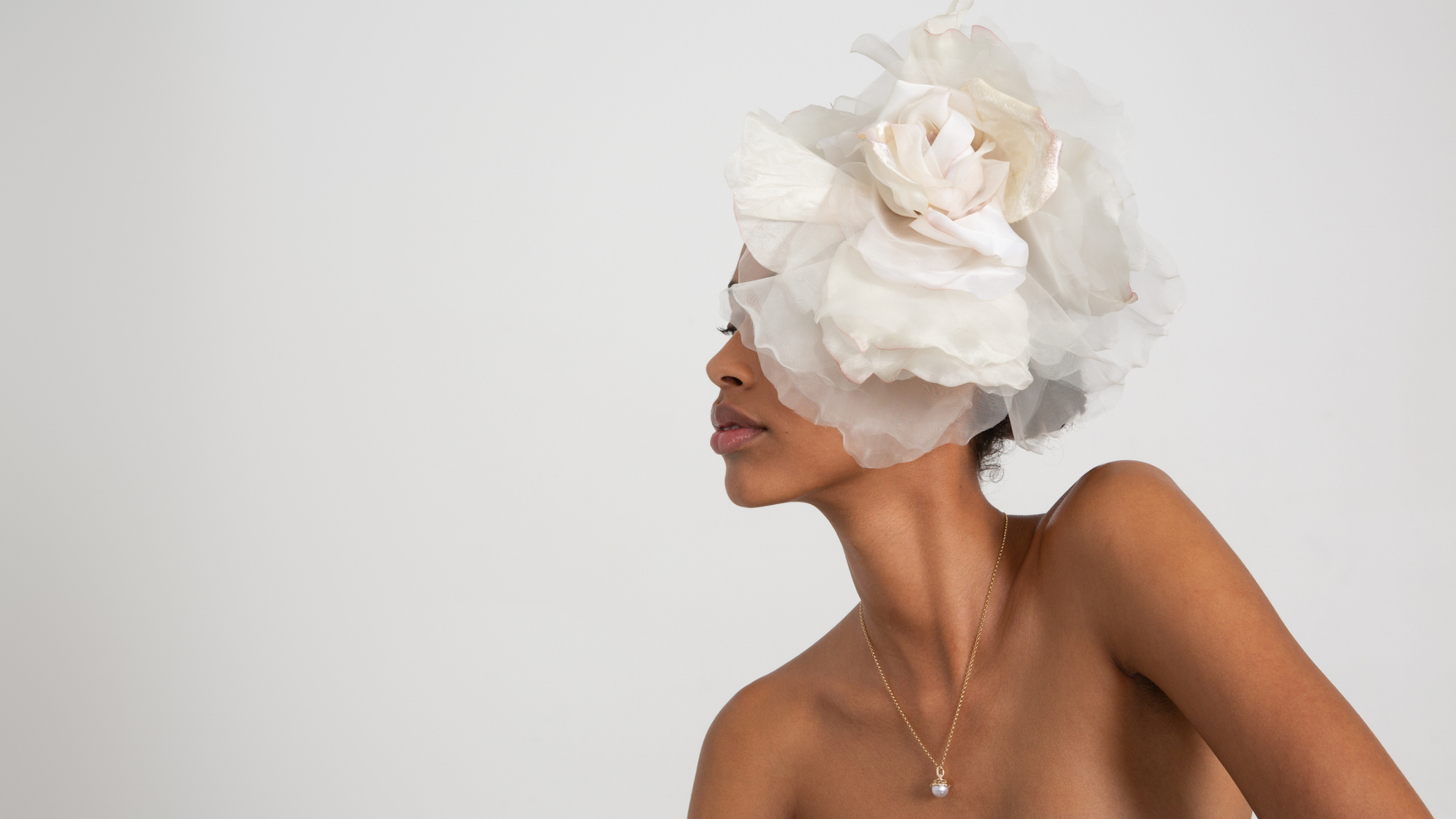 A light-complexion model wearing a black rutilated quartz pear drop earring on her right ear set on a grey background.