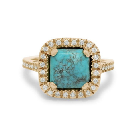 A turquoise cabochon ring with a white diamond halo and pave on the band set in 14kt yellow gold.
