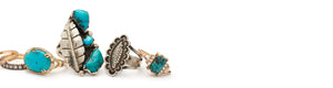 Lined up mixed metal rings that feature turquoise gemstones. Some rings lay on their sides and some are propped up vertically.