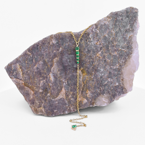 emerald y pointe necklace in yellow gold draped over a rock 2