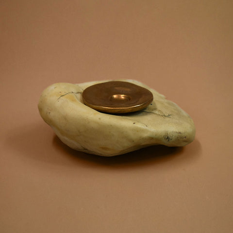 Decorative stone object with a brass disc on a brown background