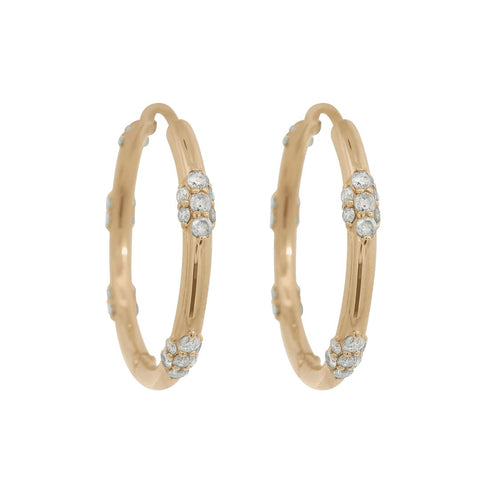 A pair of gold hoop earrings featuring clusters of grey round white diamonds on a white background 