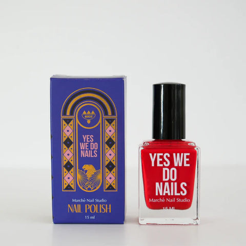 Red nail polish bottle and packaging with 'Yes We Do Nails' branding on a white background