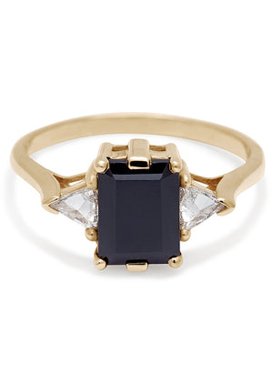 A three stone engagement ring with an emerald cut and emerald shape 8x6mm black diamond center stone with two white diamond trillion side stones set in yellow gold.