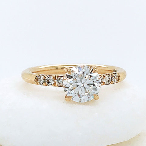 A solitaire ring with a round white diamond with 3 round white diamond stones on either side set in yellow gold on three white stones.