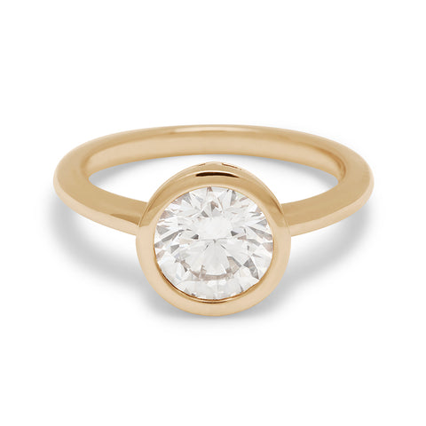 A round brilliant cut bezel set lab white diamond set in yellow gold.