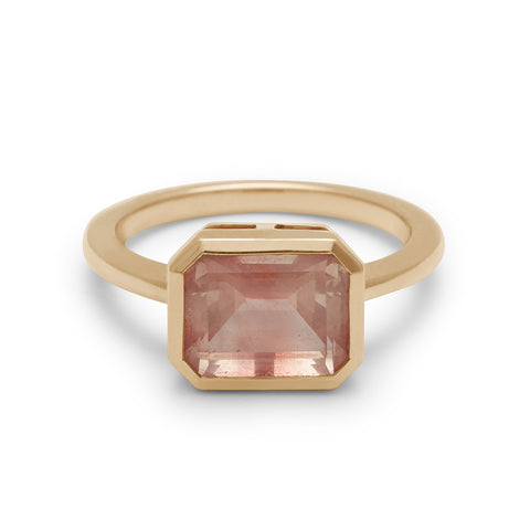 An east/west emerald shape bezel set sunstone center set in yellow gold.