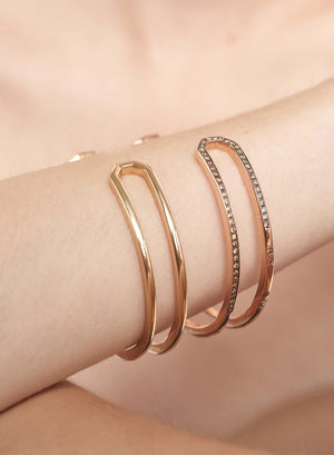 A lighter-complexion model with two cuff bracelets. The second cuff bracelets has a white diamond pave.