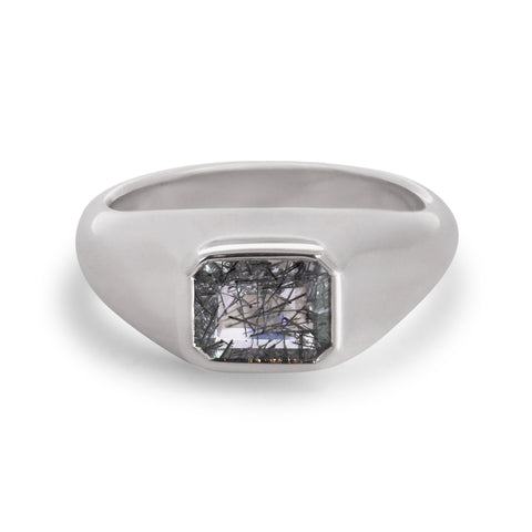 A silver ring featuring an emerald cut black and white black rutile quartz gemstone on a white background