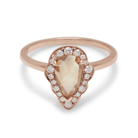 A pear shaped rose cut champagne diamond ring set in a halo of white diamonds and set in rose gold.