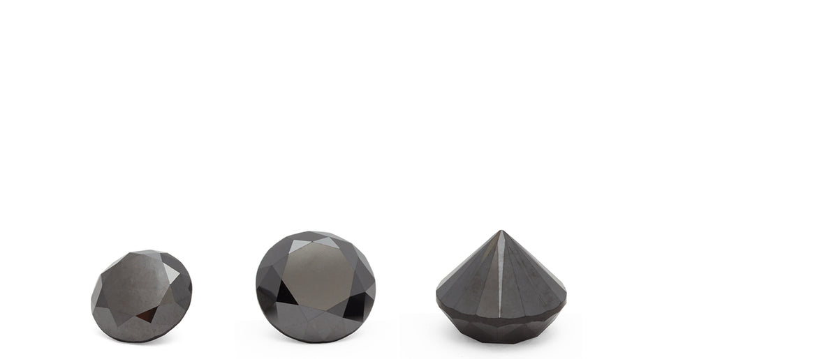 3 black diamonds sit on a flat surface horizontally in varying sizes.