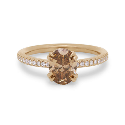 Gold ring with an oval brown diamond and white diamond accents on a white background