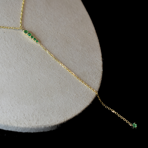 flat-lay of emerald y pointe necklace in yellow gold
