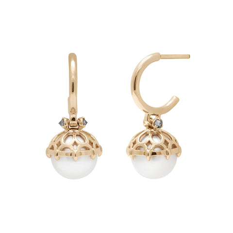 A pair of hoops with a white pearl hanging from it with grey diamond accents on either side set in yellow gold one earring angled.
