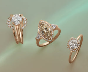 A stack of a round white diamond ring stacked between two white diamond curve bands next to two diamond halo engagement rings on a green background.