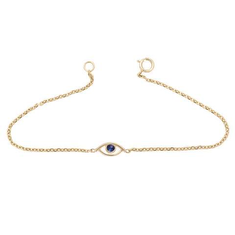 An evil eye charm with a blue sapphire stone center set in yellow gold on a yellow gold chain bracelet.