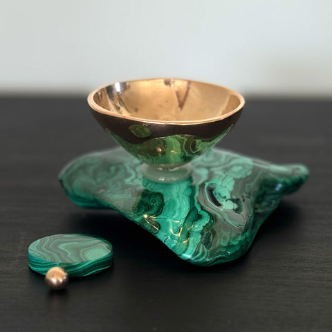 Green and gold decorative item on a dark surface with a white background