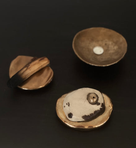 Three golden bronze dish objects on a black background