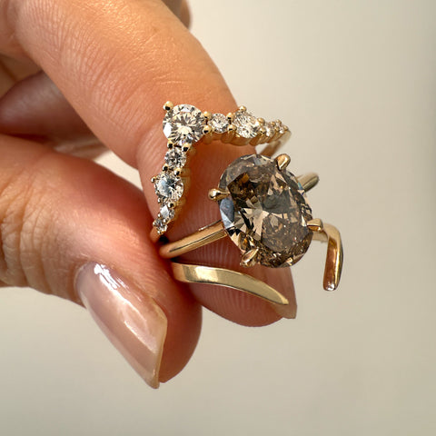 Two gold rings with gemstones held by a hand against a neutral background 2