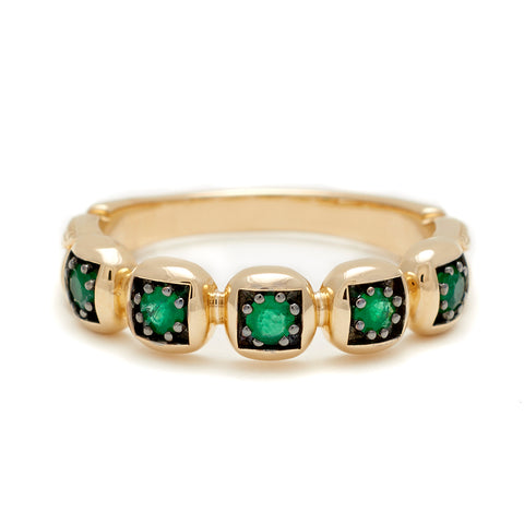 A band with round emerald stones set in black rhodium and in yellow gold.