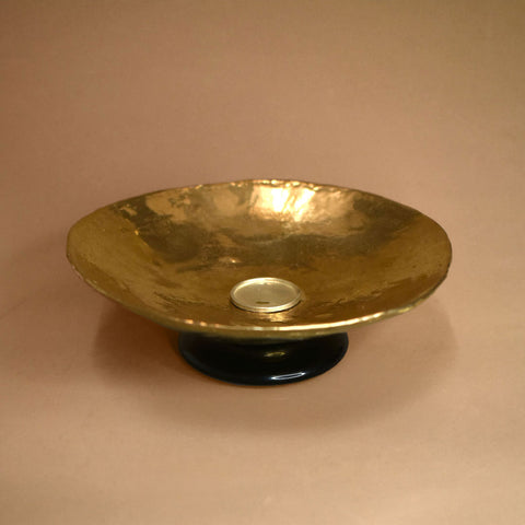 A bronze dish with a black jasper base on a beige background