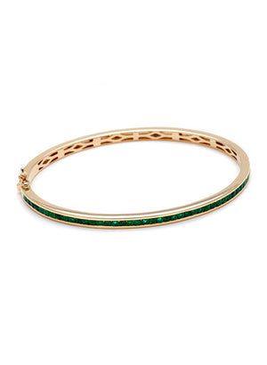 A bracelet with a line of emeralds set around the band set in yellow gold.